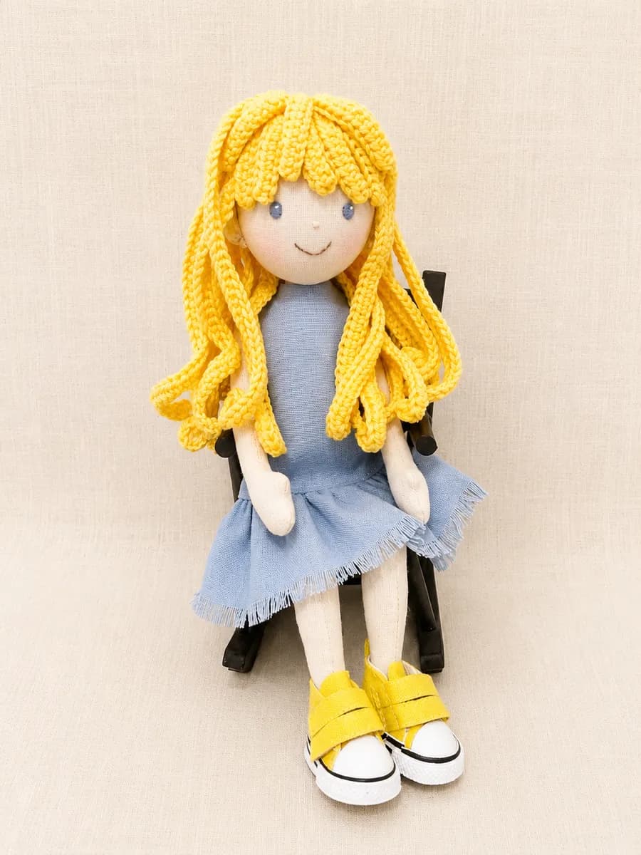 Boneca de pano de cabelo amarelo com blusa e saia azul