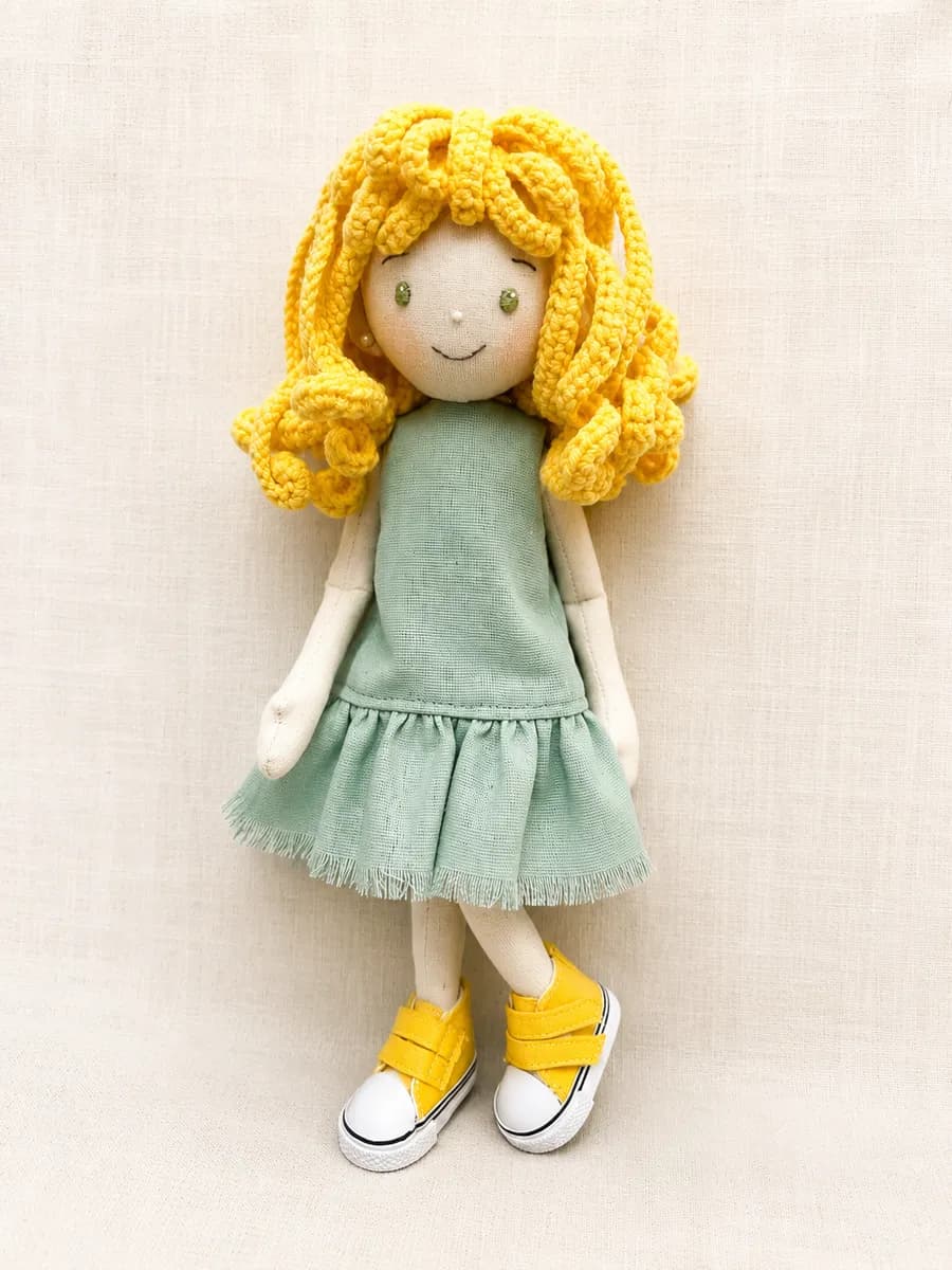 Boneca de pano com cabelo amarelo cacheado e vestido verde